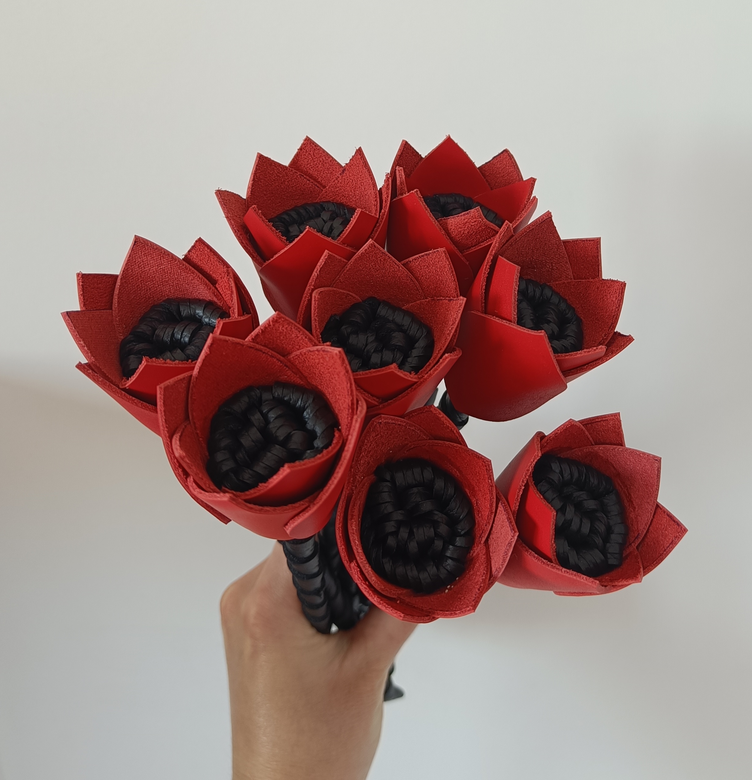 Vue en main de Bouquet de fleurs en cuir rouge et noir upcyclé, fait main en France